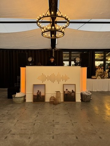 The white Dynamic Celebrations DJ booth lit under the pavilion chandeliers