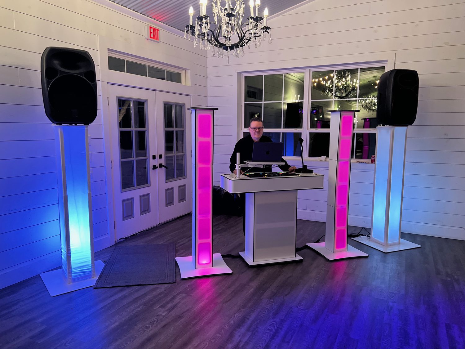 The DJ booth lit in blue and pink at a reception